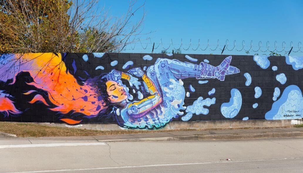 Mural of a woman adorned in robot-like gear along the outer wall of the Kashmere bus operating facility at 5700 Eastex Freeway in Houston